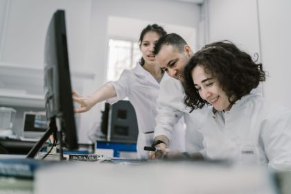 Equipe diversa de cientistas trabalha em conjunto diante de um computador em um laboratório moderno.