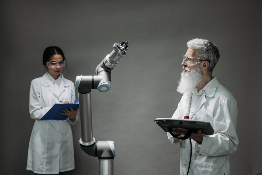 Dois pesquisadores analisam um braço robótico em um laboratório de tecnologia.