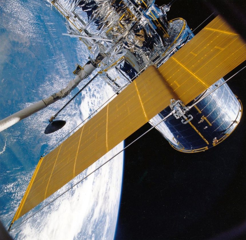 Espaçonave com painéis solares orbitando a Terra, vista contra o espaço.